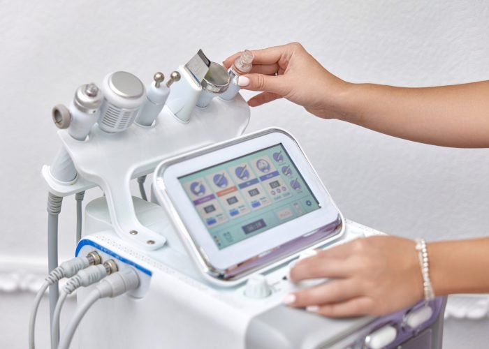 female beautician using cosmetology equipment in modern aesthetic clinic.