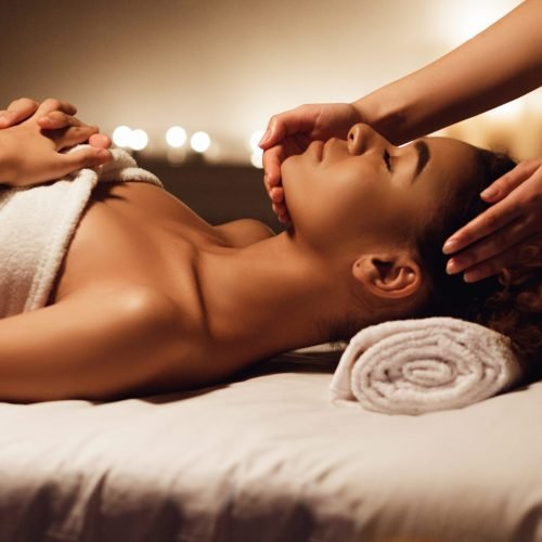 Face massage. African-american woman getting spa treatment, side view